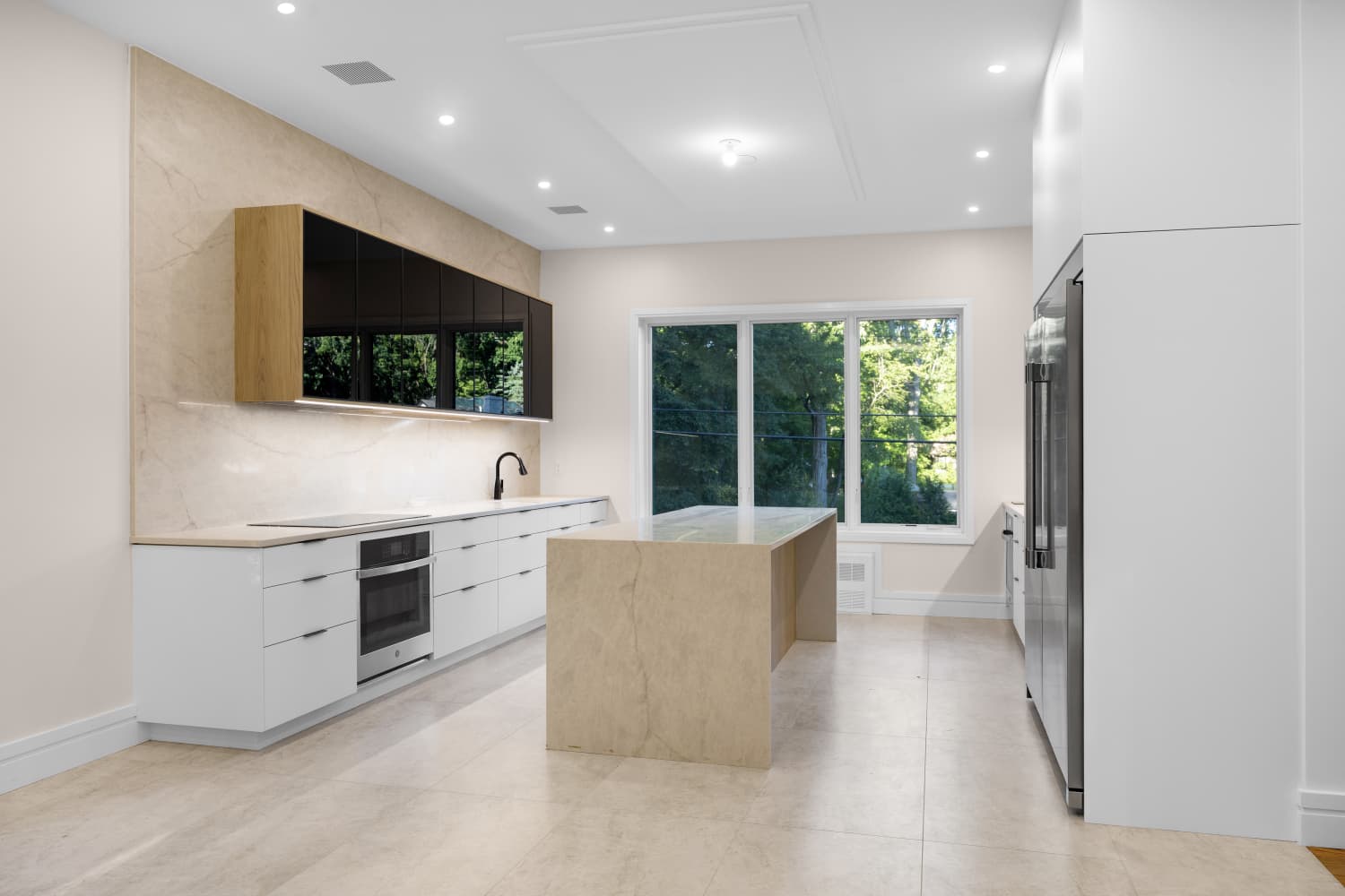 White kitchen with a stone island and black glass upper cabinets