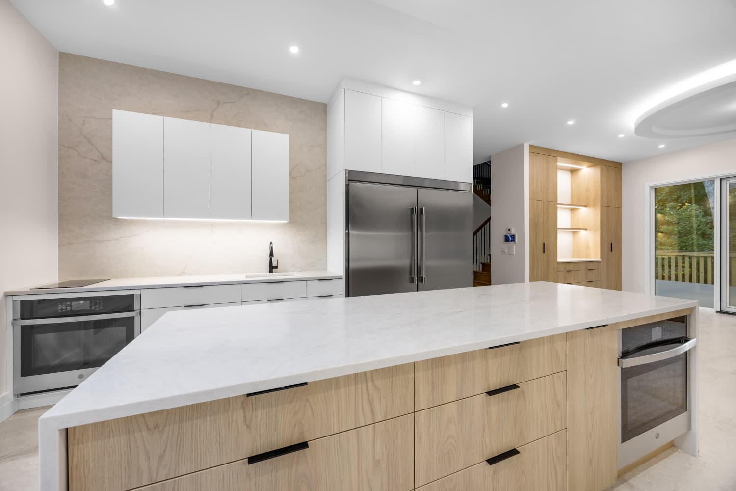 Kitchen with a wood island, white cabinetry and stainless steel refrigerator