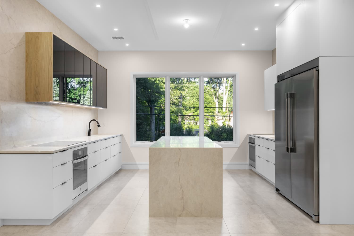 Kitchen showing a stone island, black glass cabinets and stainless steel refrigerator