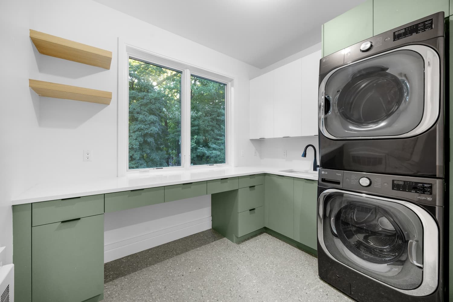 Laundry room with a green cabinet desk run, floating oak shelves and a window