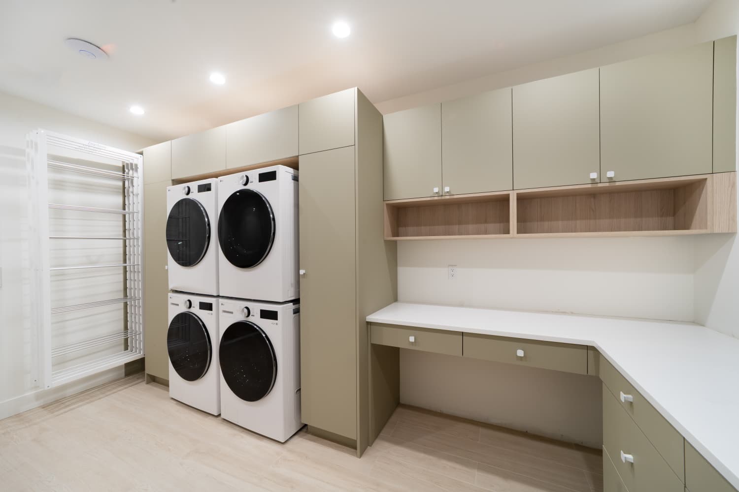Laundry room with sage cabinets, four stacked machines and a drying rack